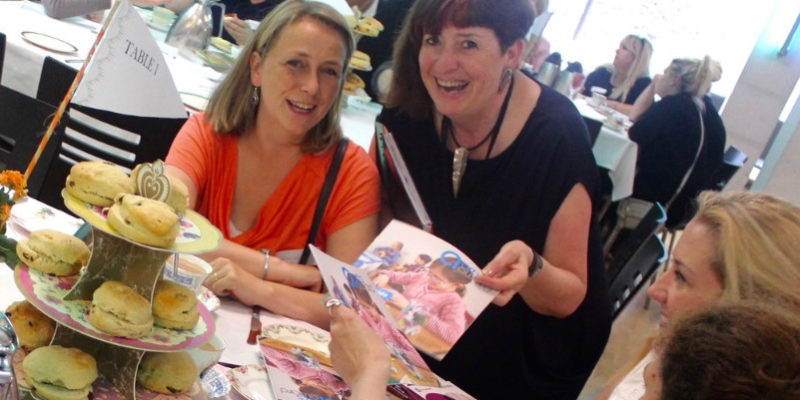 Pepita Hanna smiles with a Tea Party delegate at a tea party table covered in cake