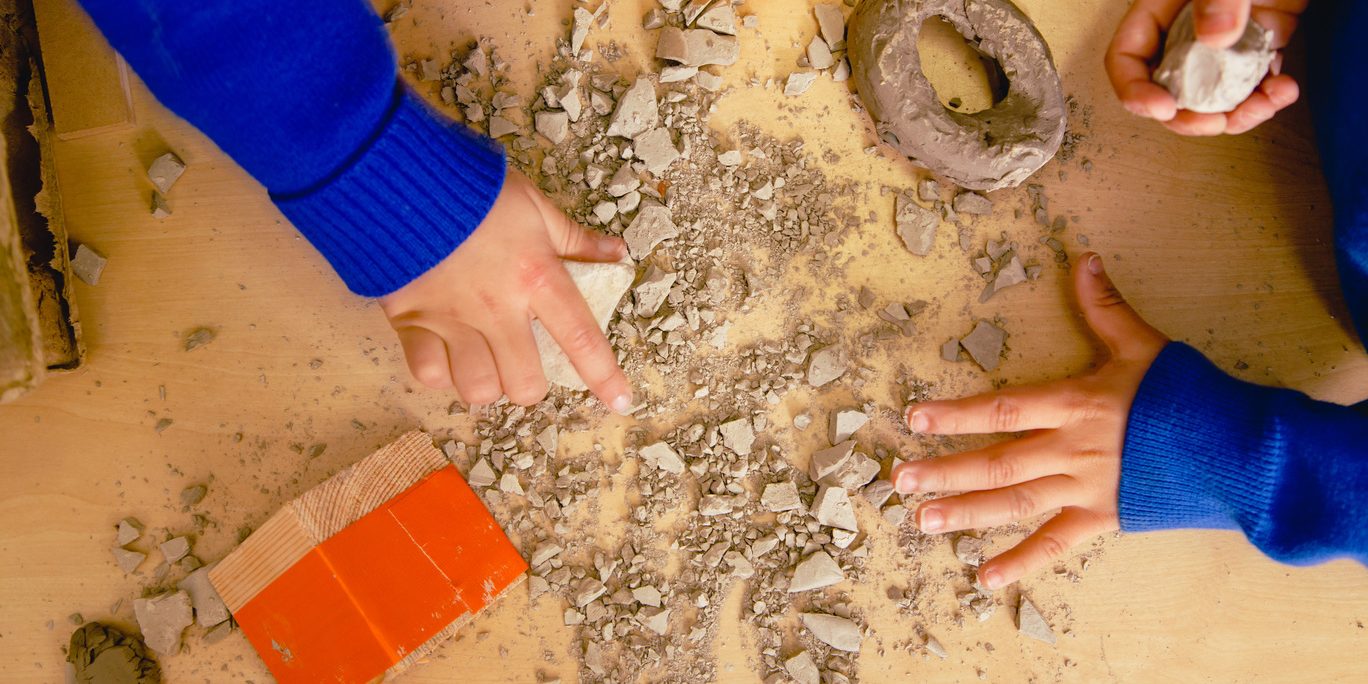 The hands of primary aged school children playing with clay