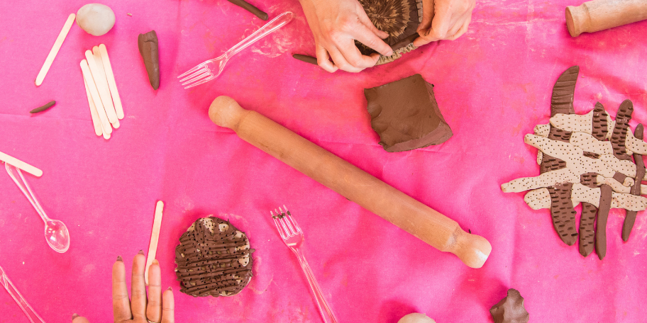 Half Term Creative Family Workshop Make your own ‘Plant Theatre’ costumes. (1) Web card promoting a clay family workshop with photo of adult hands rolling clay to create clay circles on a table covered in a bright pink cloth