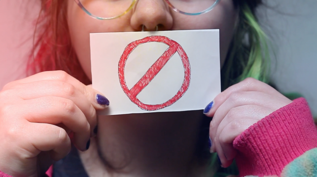 neurospicy image a woman holds a no access sign over her mouth